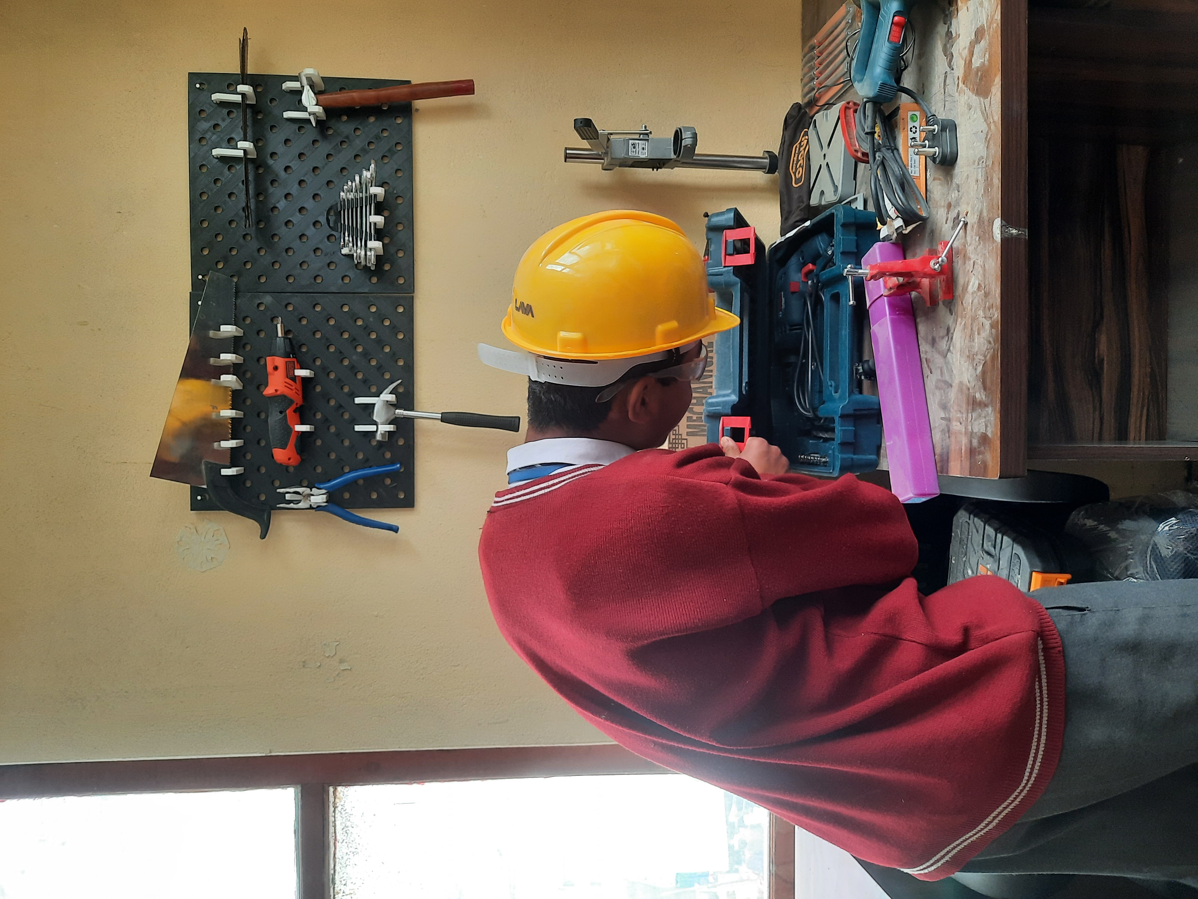 Student in a safety helmet working at the Atal Tinkering Lab workbench with tools